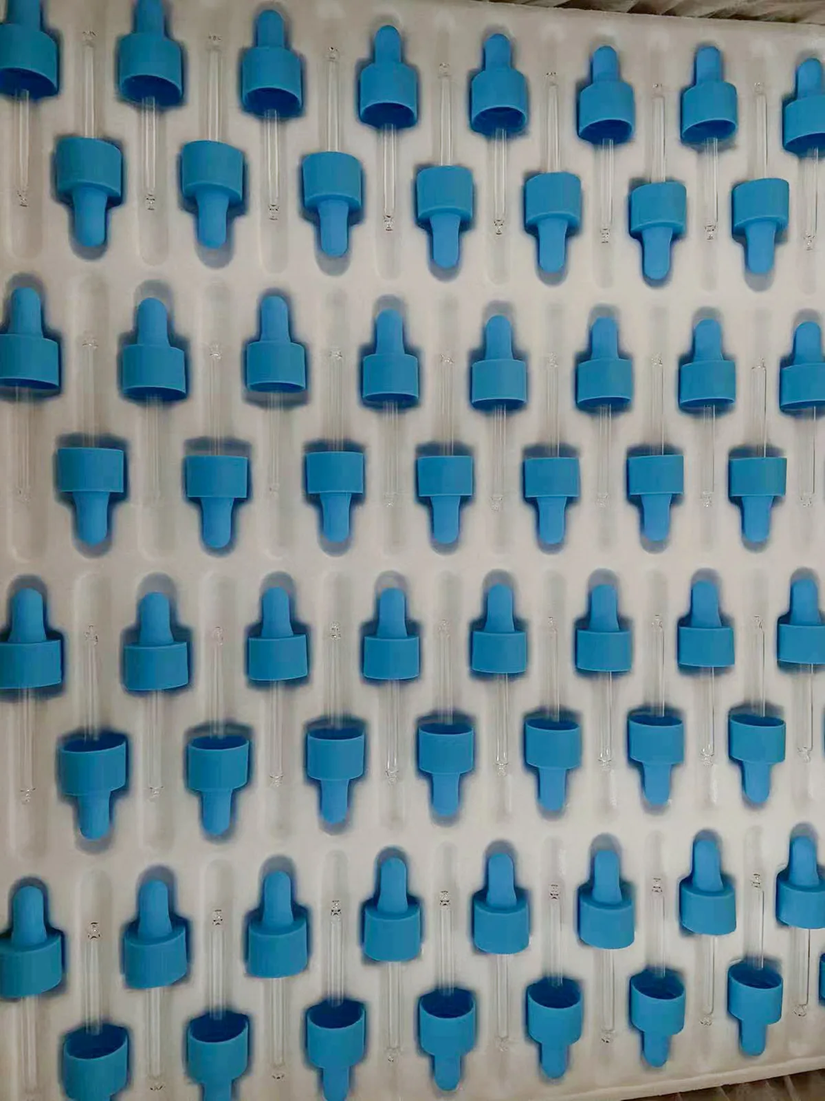 Blue cosmetic packaging components arranged in rows