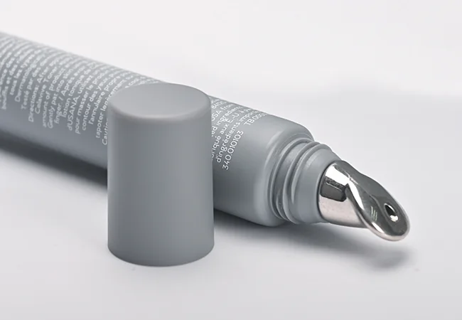 Grey cosmetic tube with exposed metal applicator